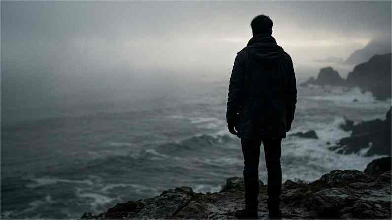 A lone figure standing on a misty stormy shore, reflecting the quiet emotional depth Pisces often keeps hidden